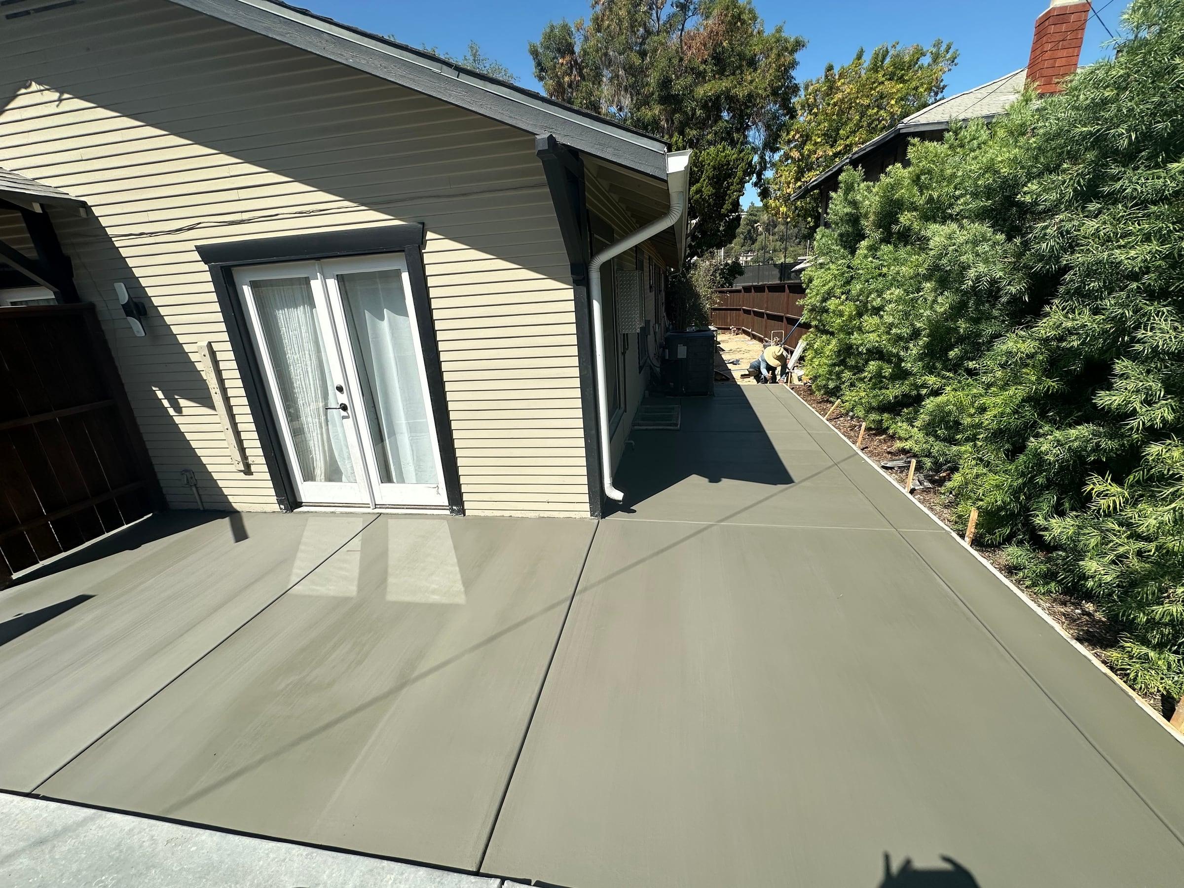 New concrete side patio running the length of a house