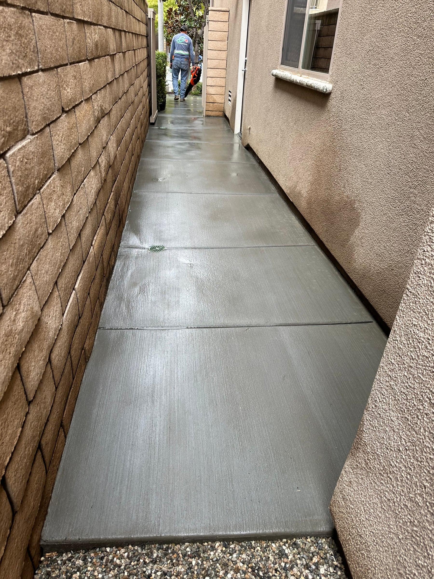 New concrete walkway between a block wall and the house