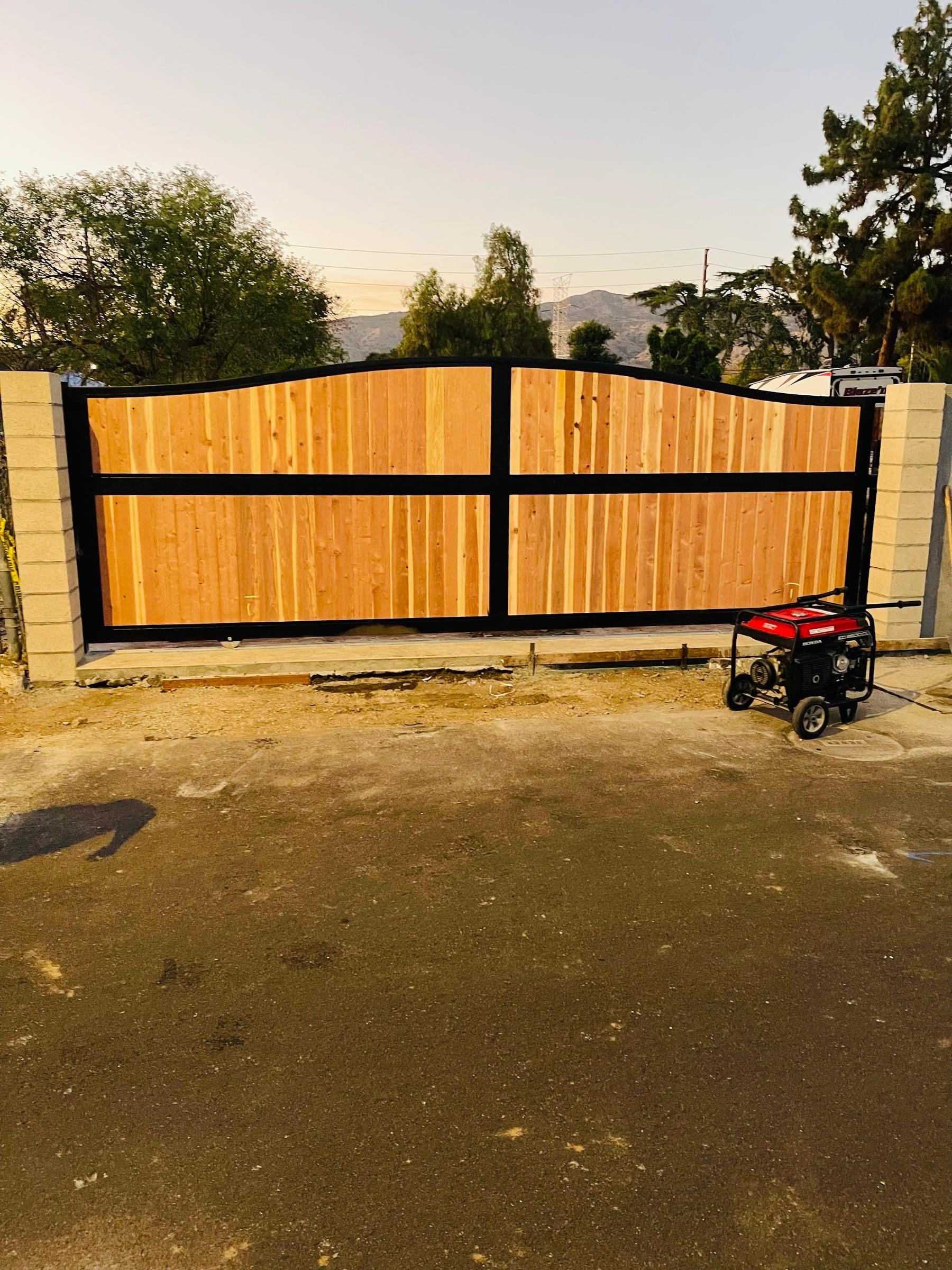 Arched wood driveway gate with black metal frame