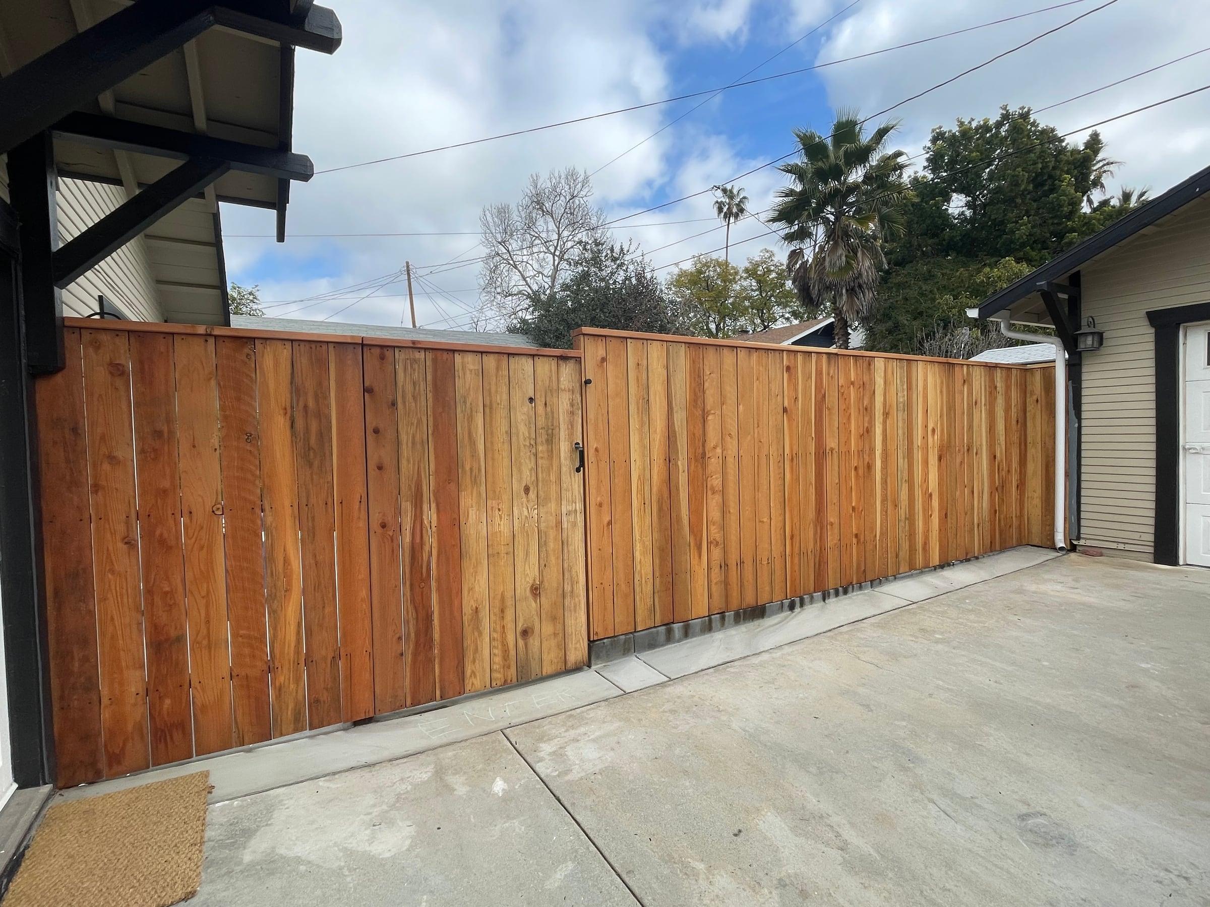 Vertical wood privacy fence and gate along a driveway