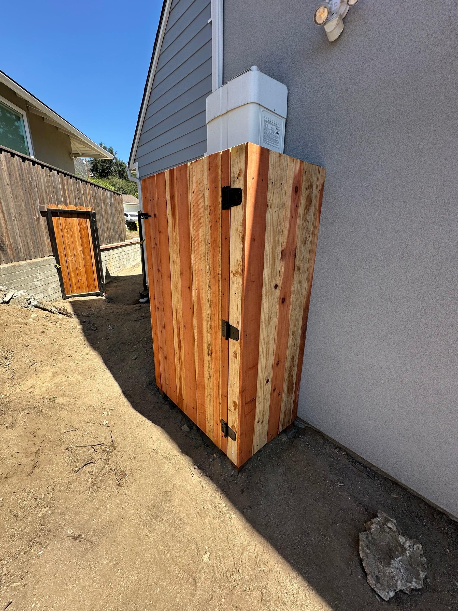 Redwood enclosure gate concealing outdoor utility equipment