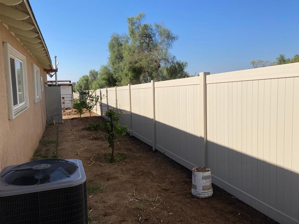 White PVC fence along a side yard with new plantings