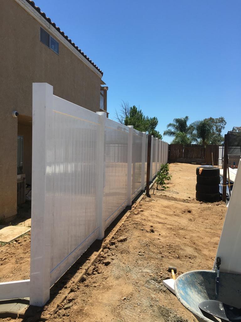 White PVC fence along a side yard with new plantings