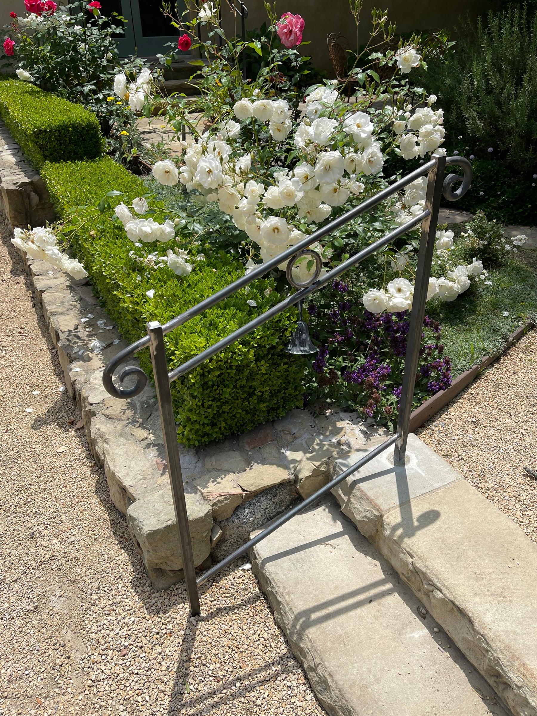 Custom black iron fencing and gate installed along a residential property line