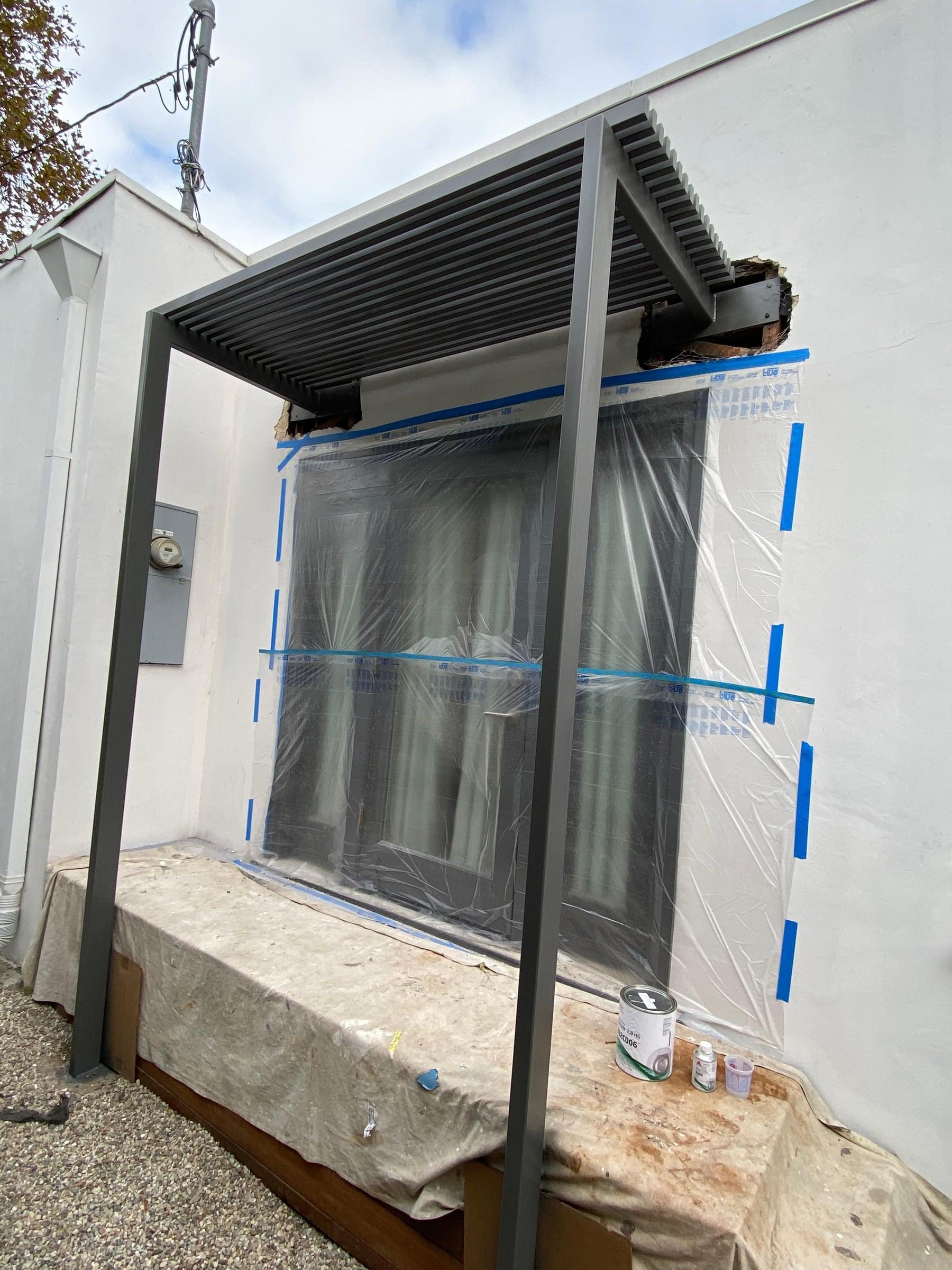 Custom metal patio cover being fabricated and installed in a backyard
