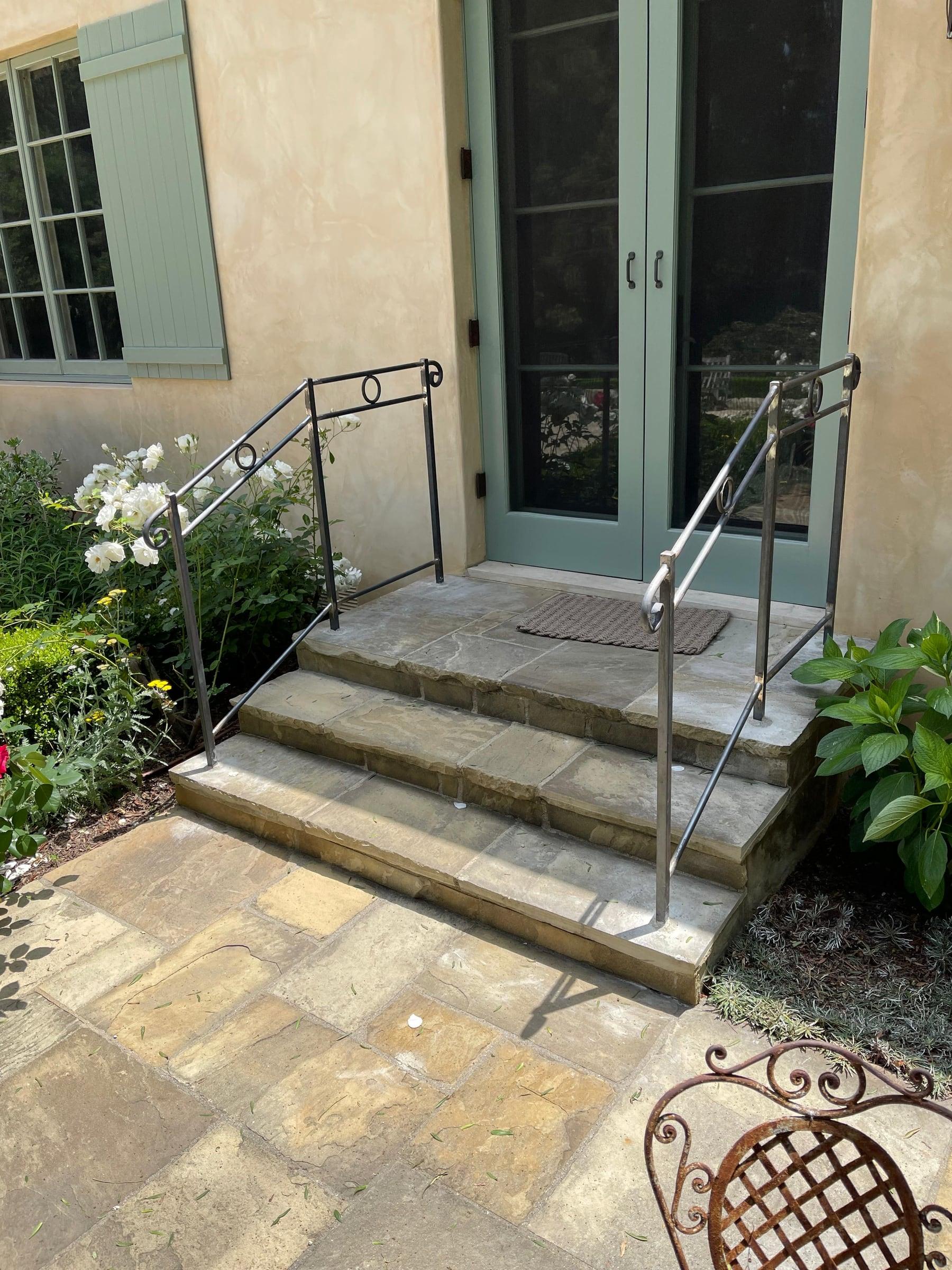 Custom iron gate with decorative scrollwork installed at a side yard entrance