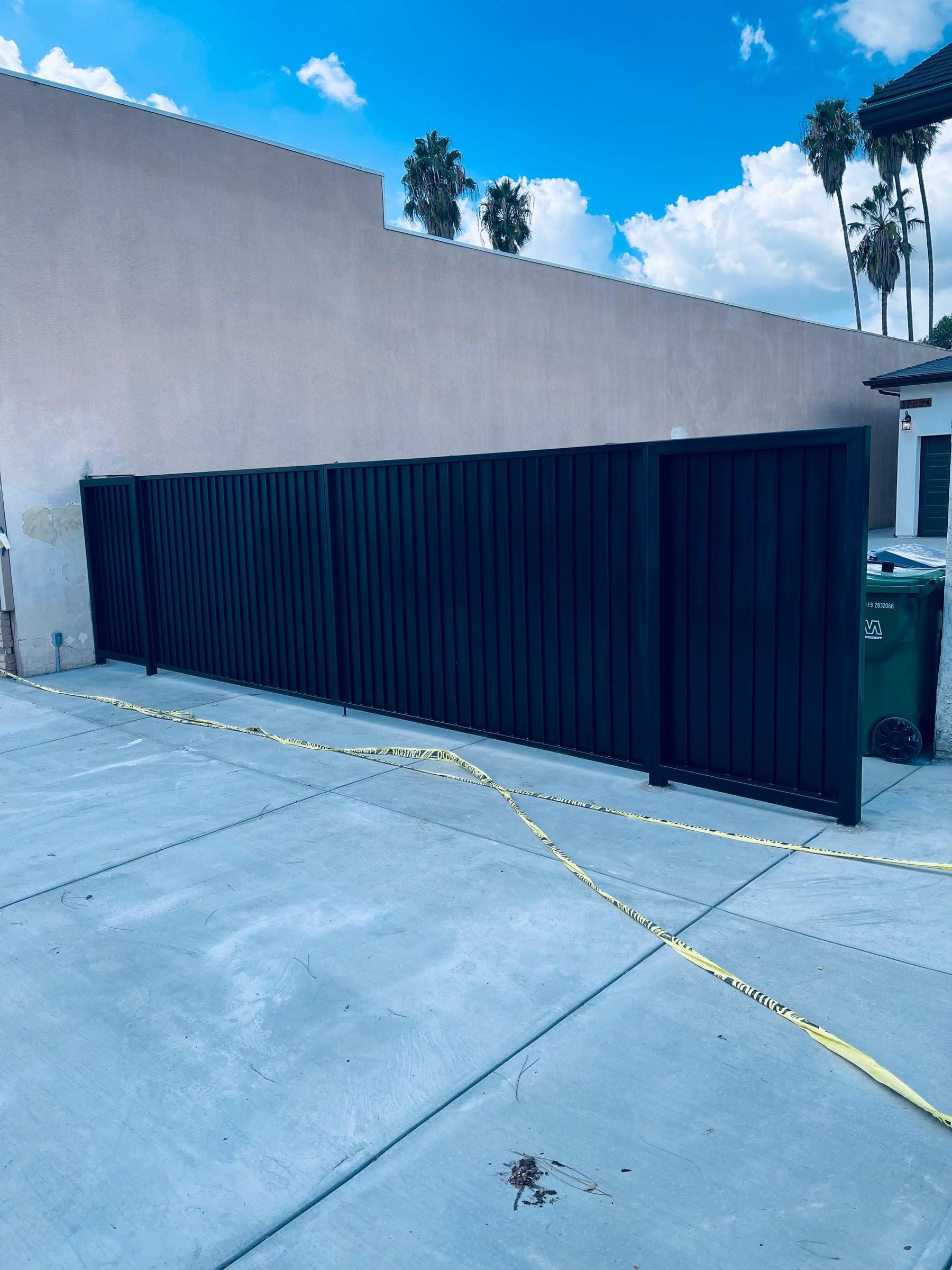 Black slatted metal driveway gate providing privacy and security