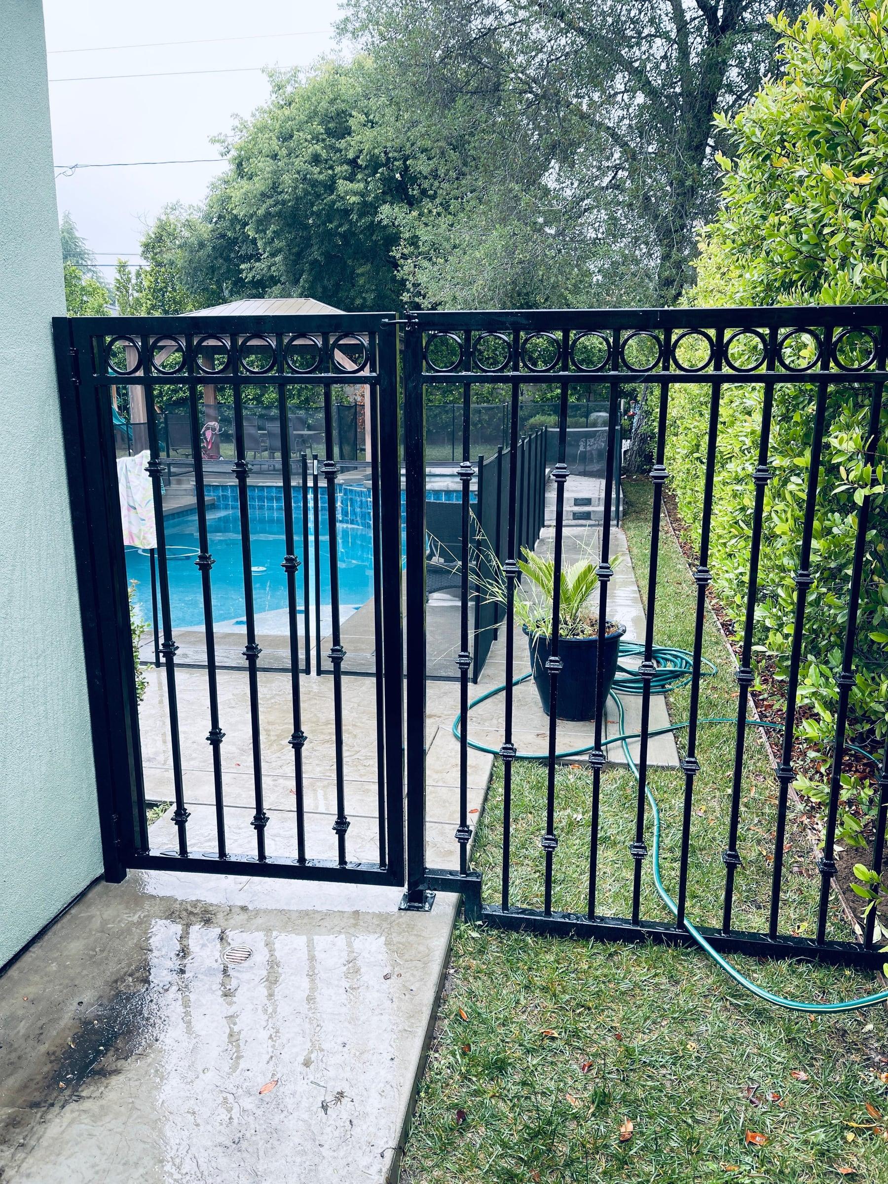 Black wrought iron pool safety gate with decorative circle pattern