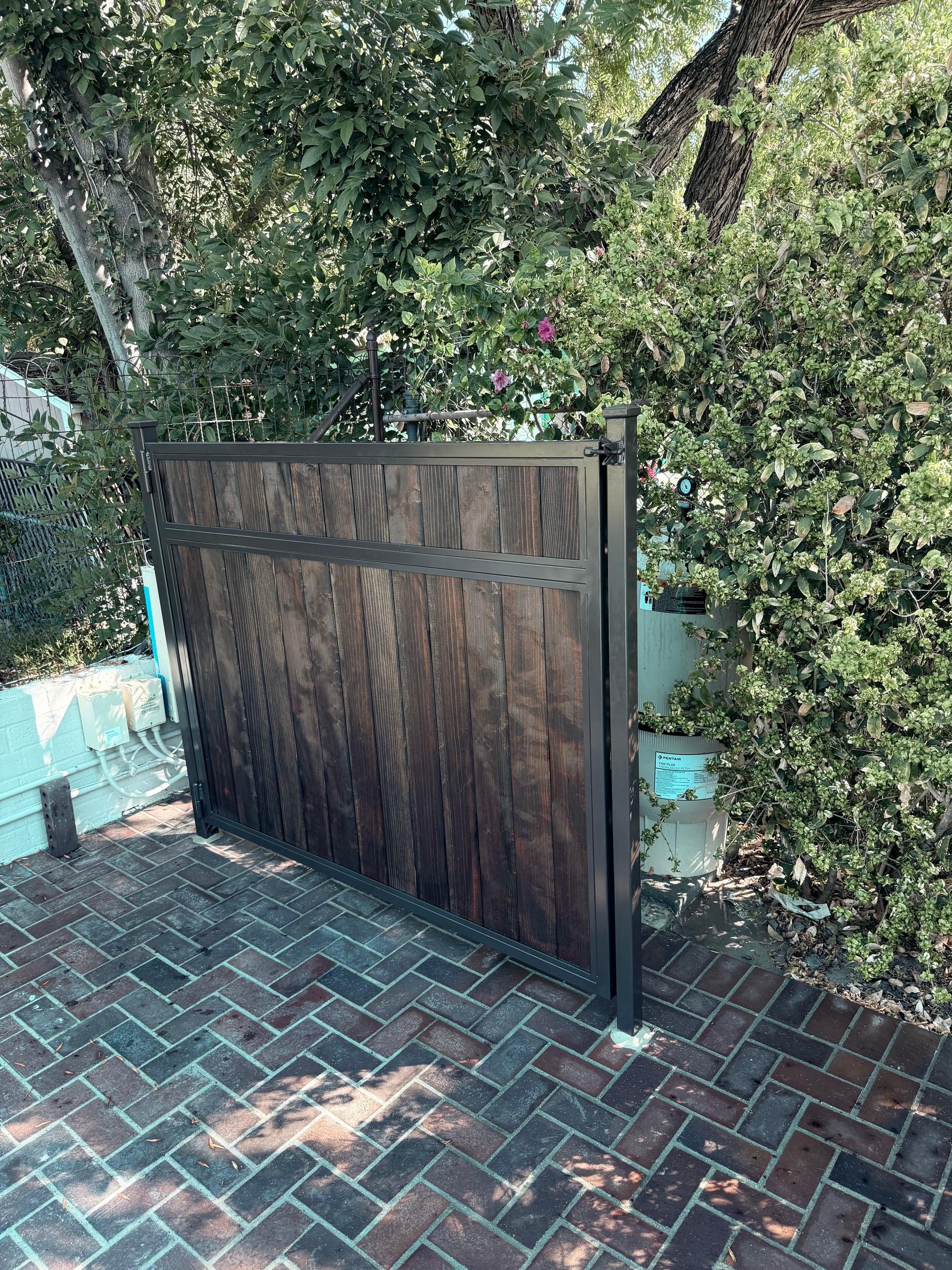 Custom wood and metal gate with dark stained panels and black metal framing