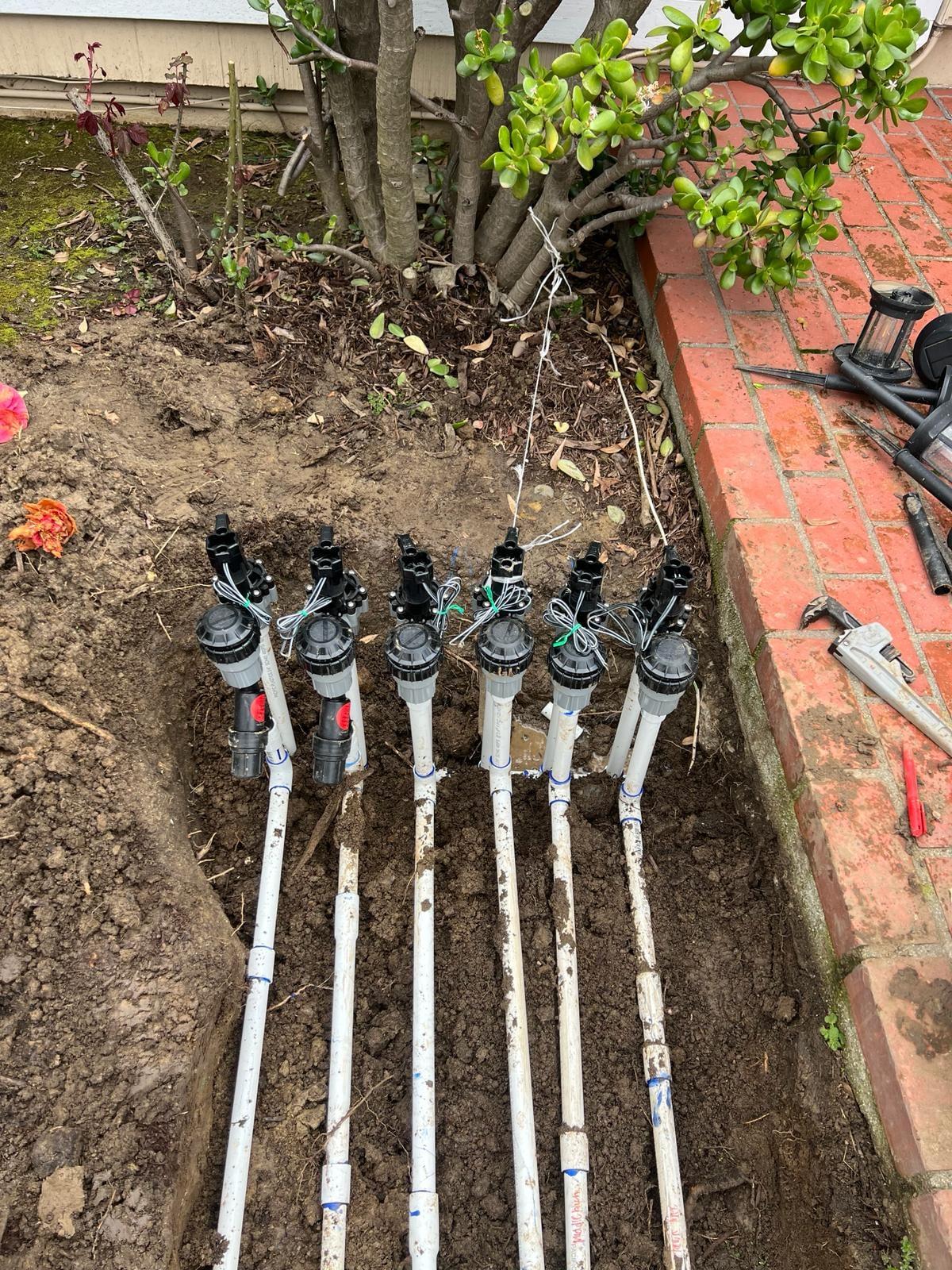 Row of new automatic irrigation valves installed in a planting bed