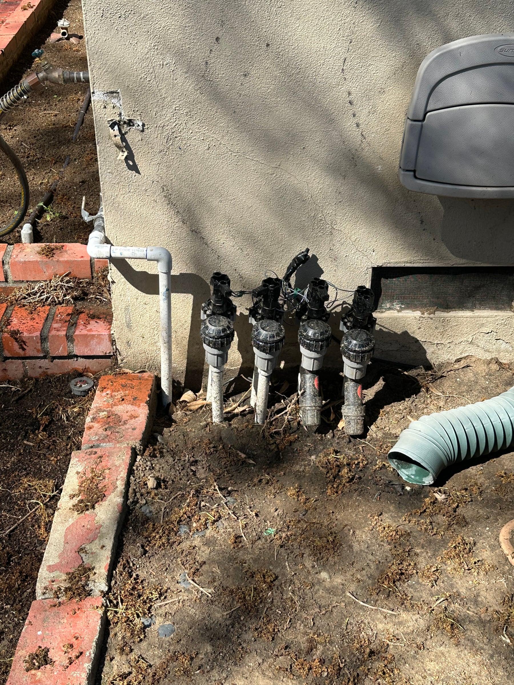 New irrigation valves installed near a brick planter edge