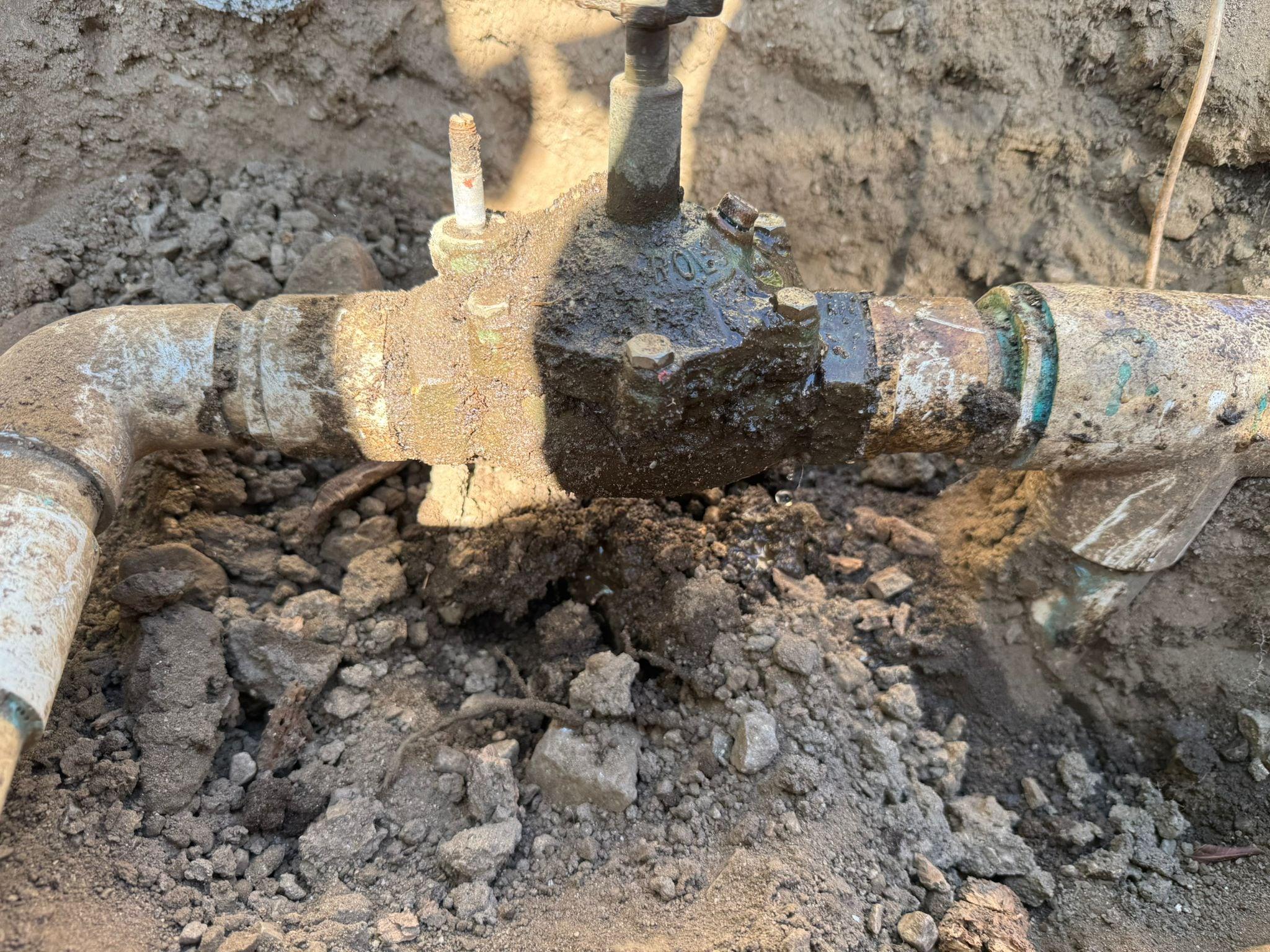 Close-up of an exposed brass irrigation valve in a trench