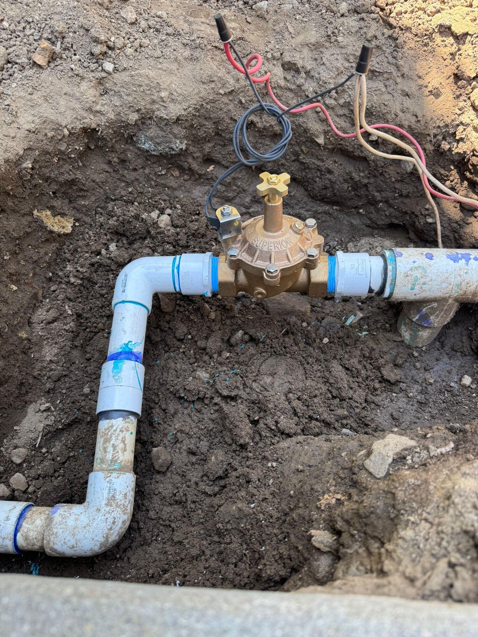 Brass irrigation valve installed in a trench with control wiring