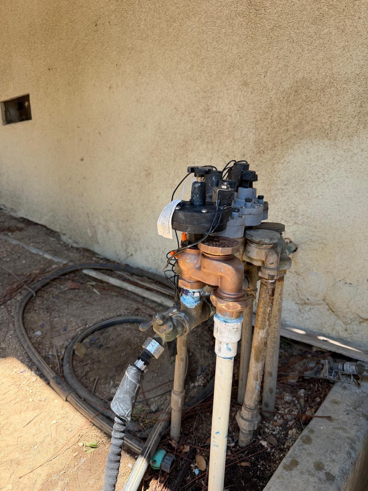 Multi-valve manifold with brass fittings and hose bib along a wall