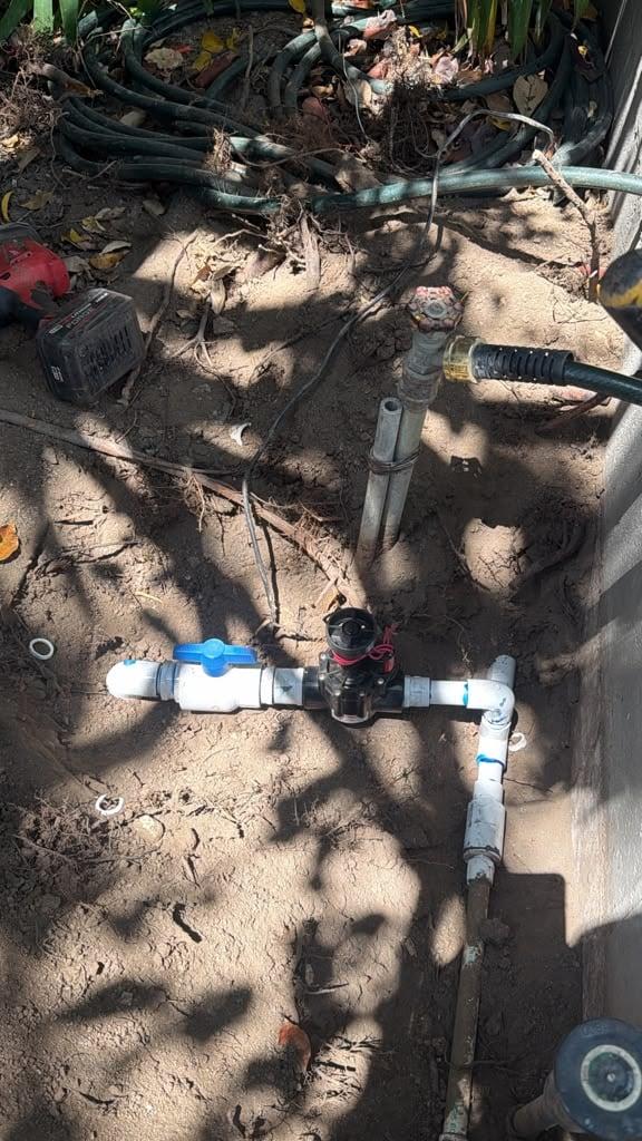 New PVC main line with a ball valve installed along a side yard wall