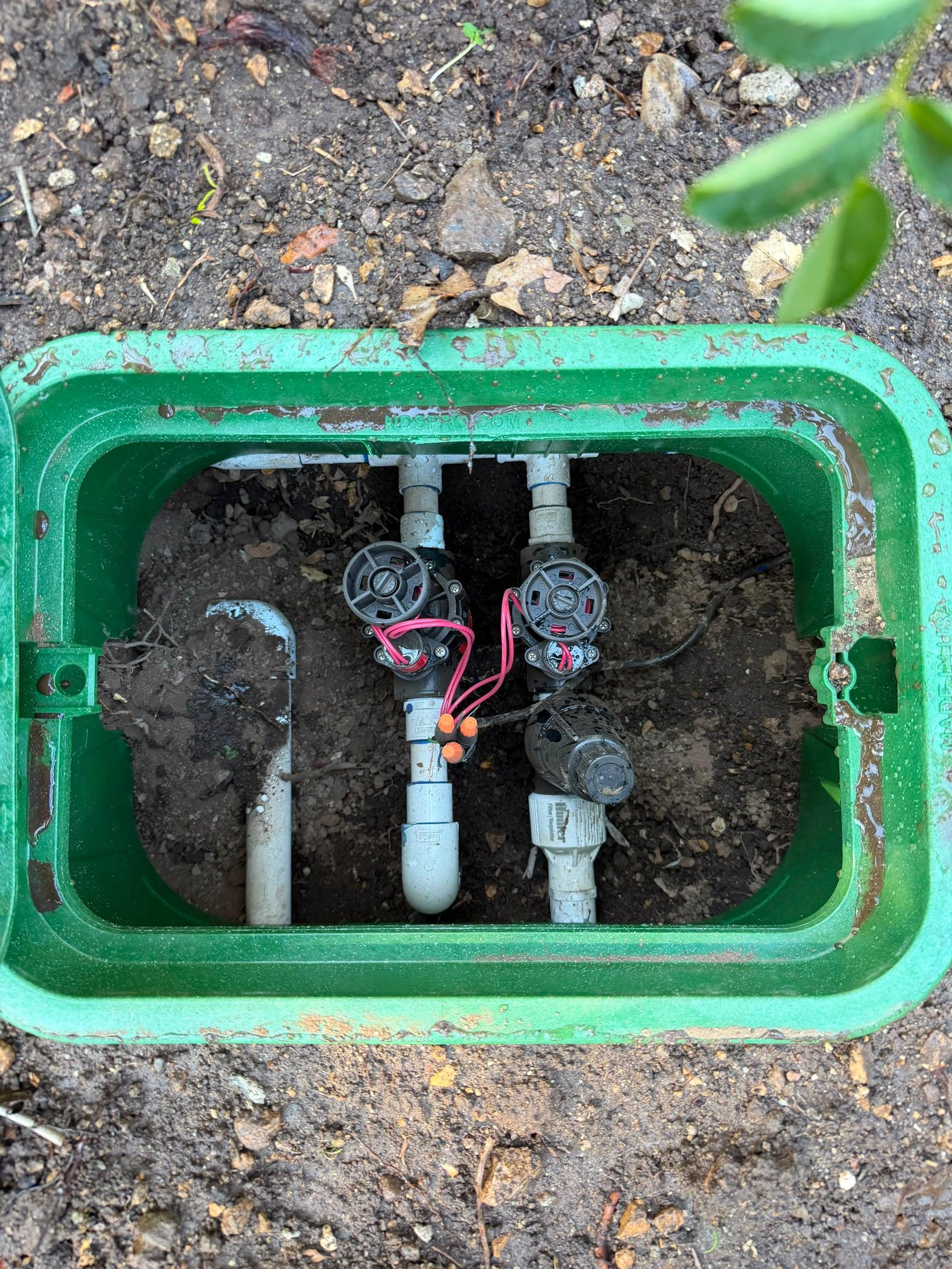 Open valve box showing solenoid valves and a pressure regulator