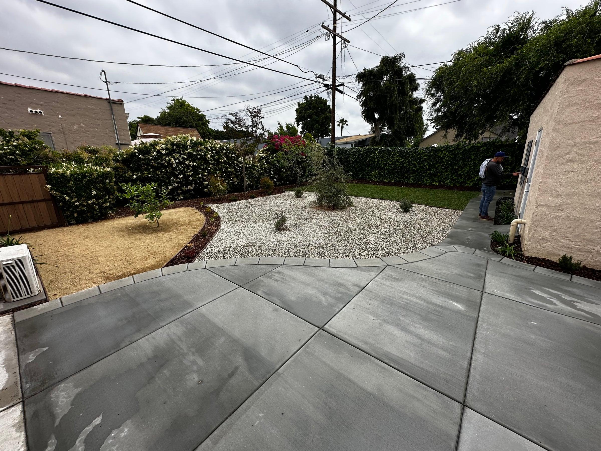 Backyard patio with a decomposed granite planting bed and olive tree