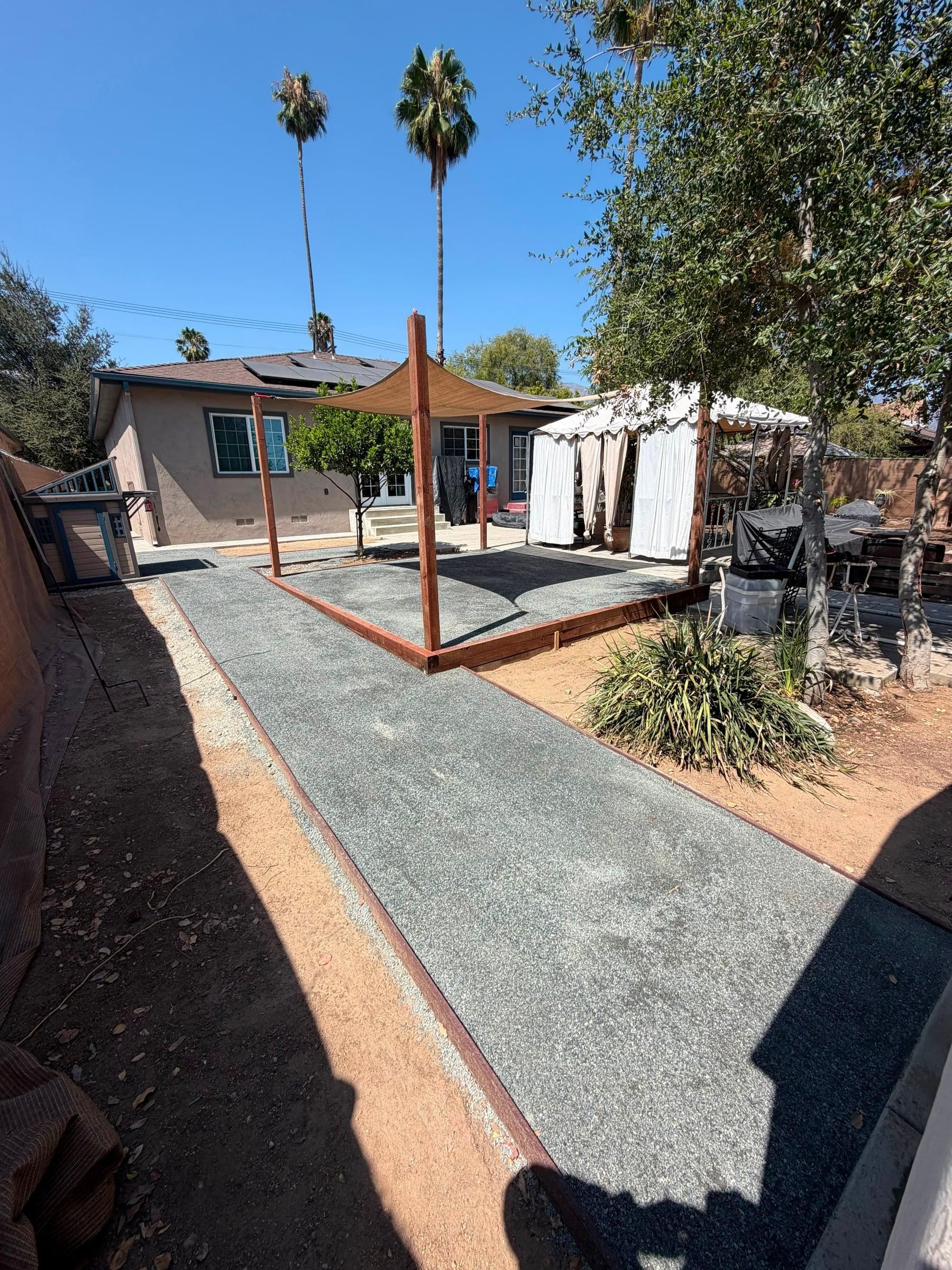 Backyard gravel patio with a shade sail and citrus tree