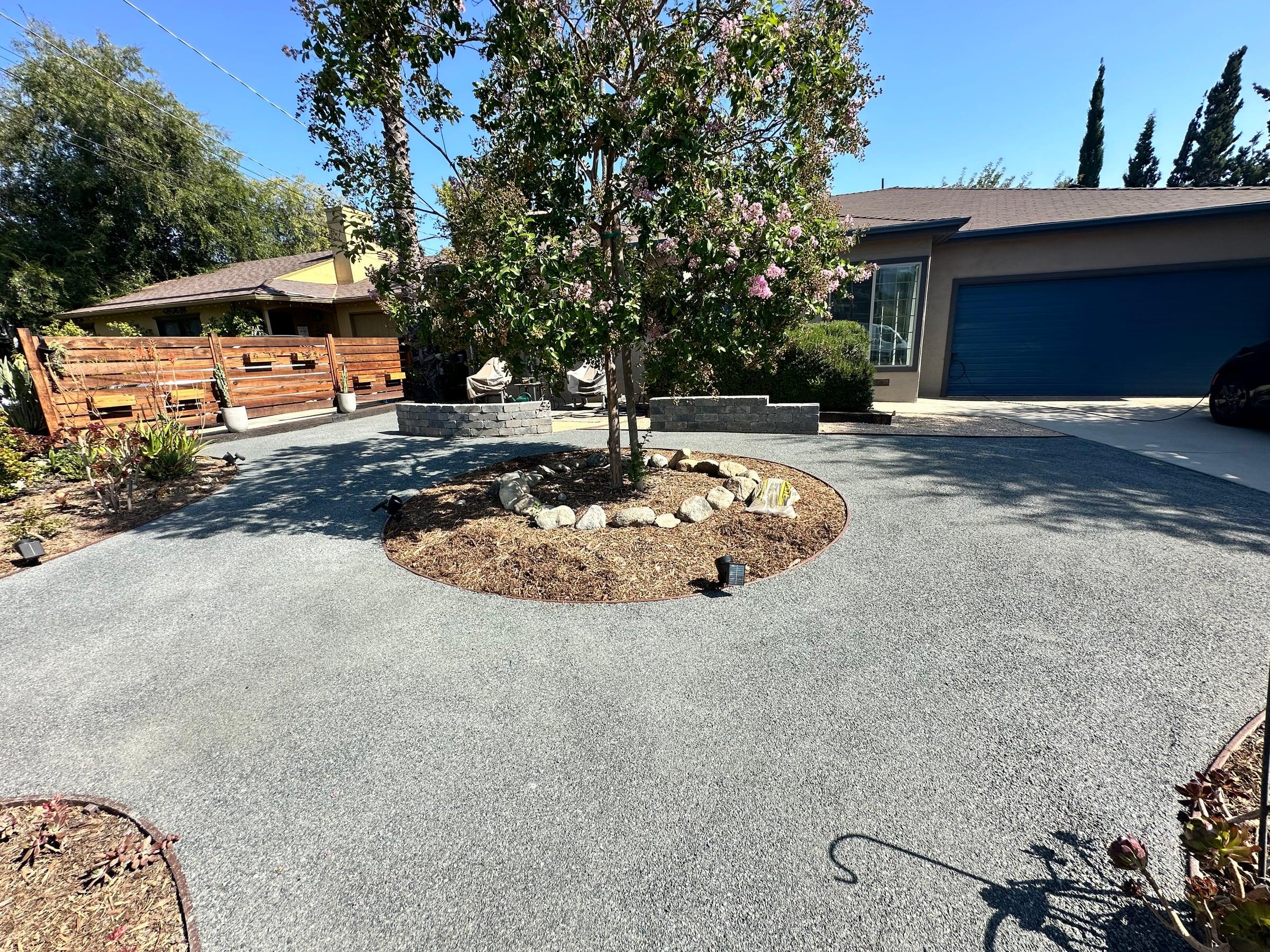 Circular mulch planting bed with a mature tree in a paver driveway