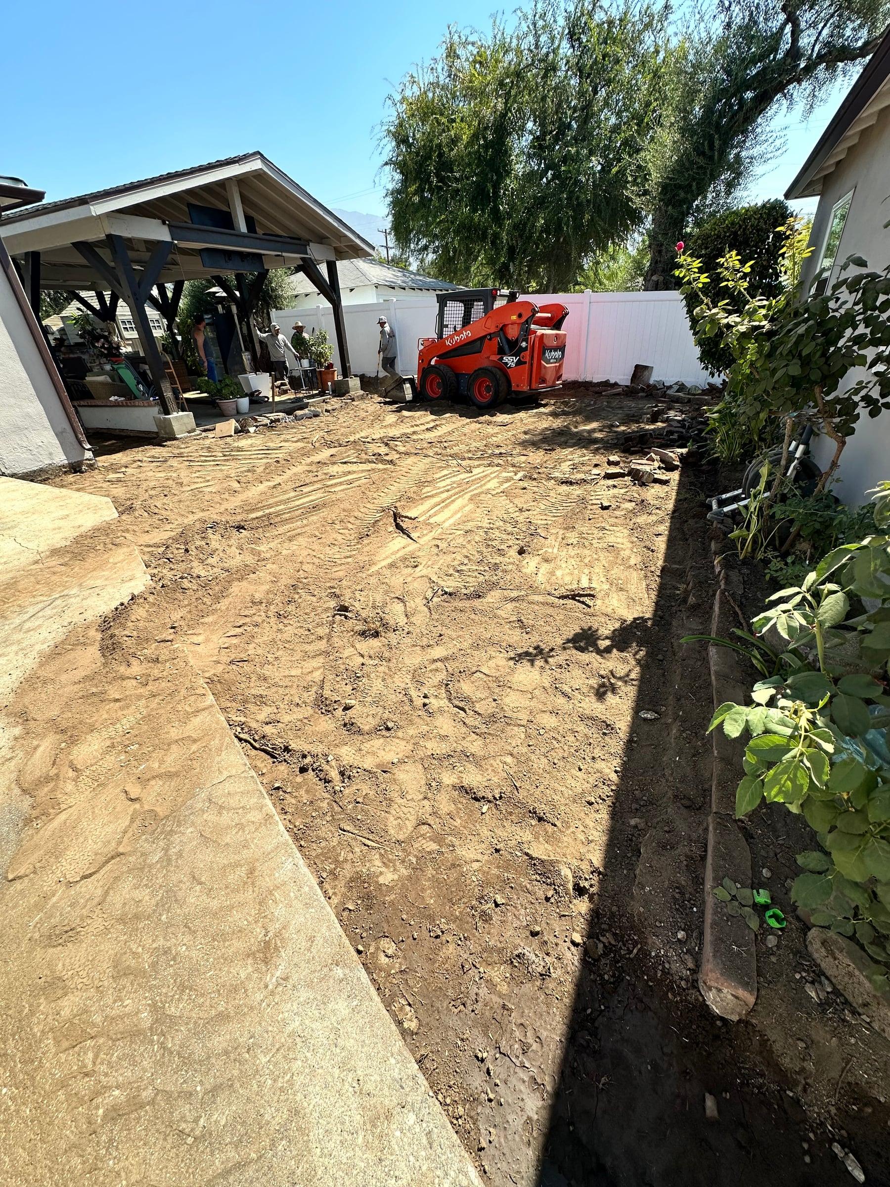 Skid steer grading a backyard for a new patio