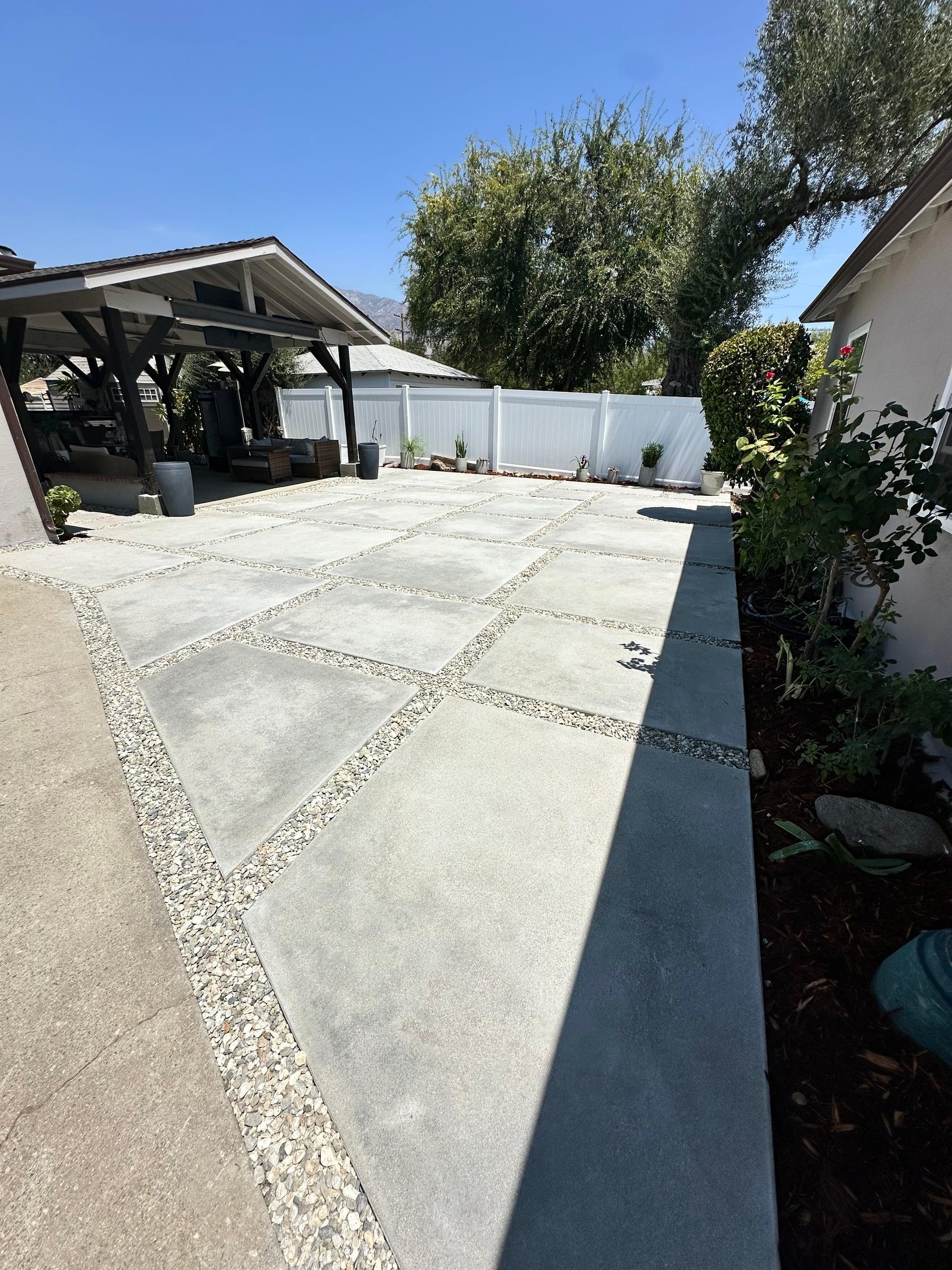 Backyard paver patio with pebble joints and an olive tree