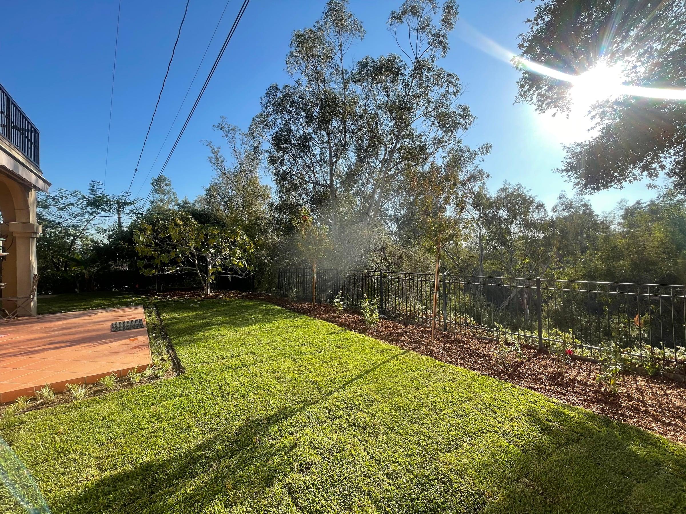 Manicured lawn along a hillside iron fence and patio