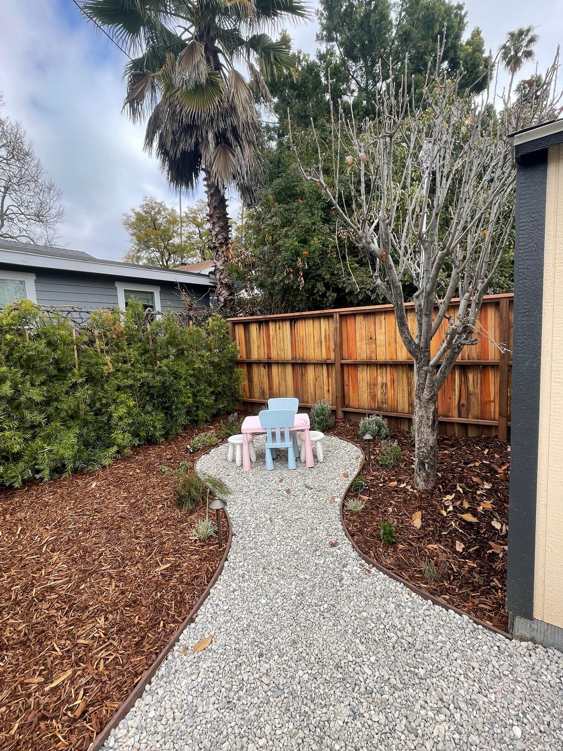 Curved gravel path leading to a backyard play area