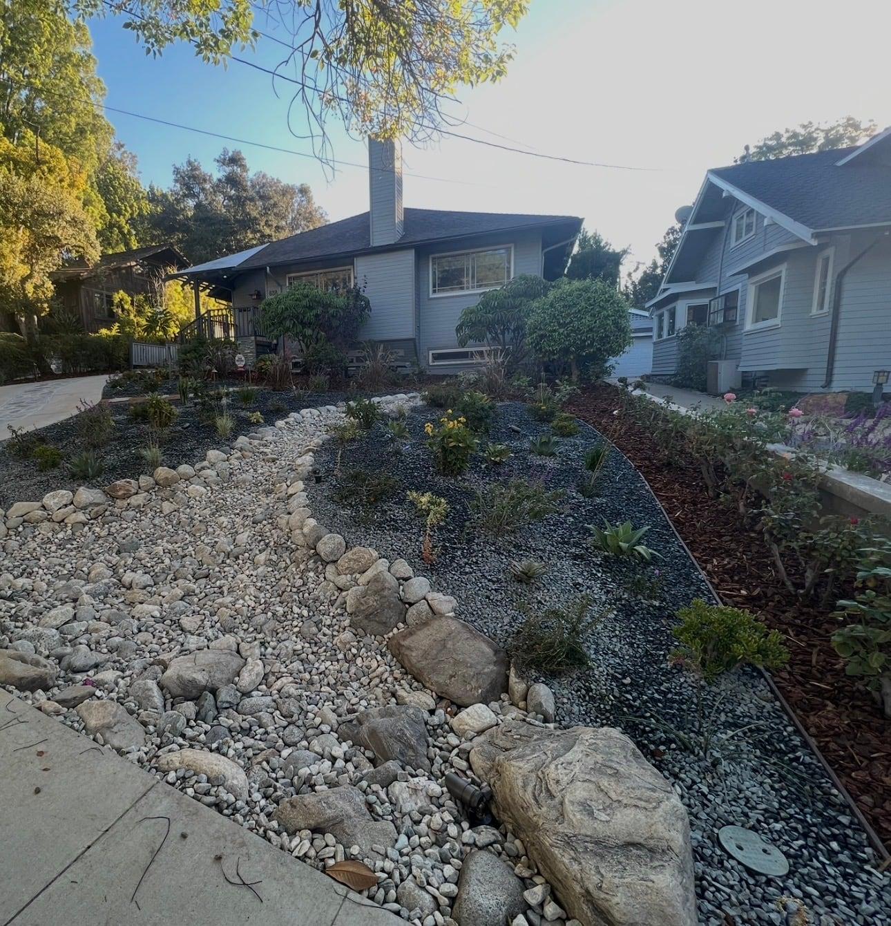 Dry riverbed rock feature with black gravel mulch