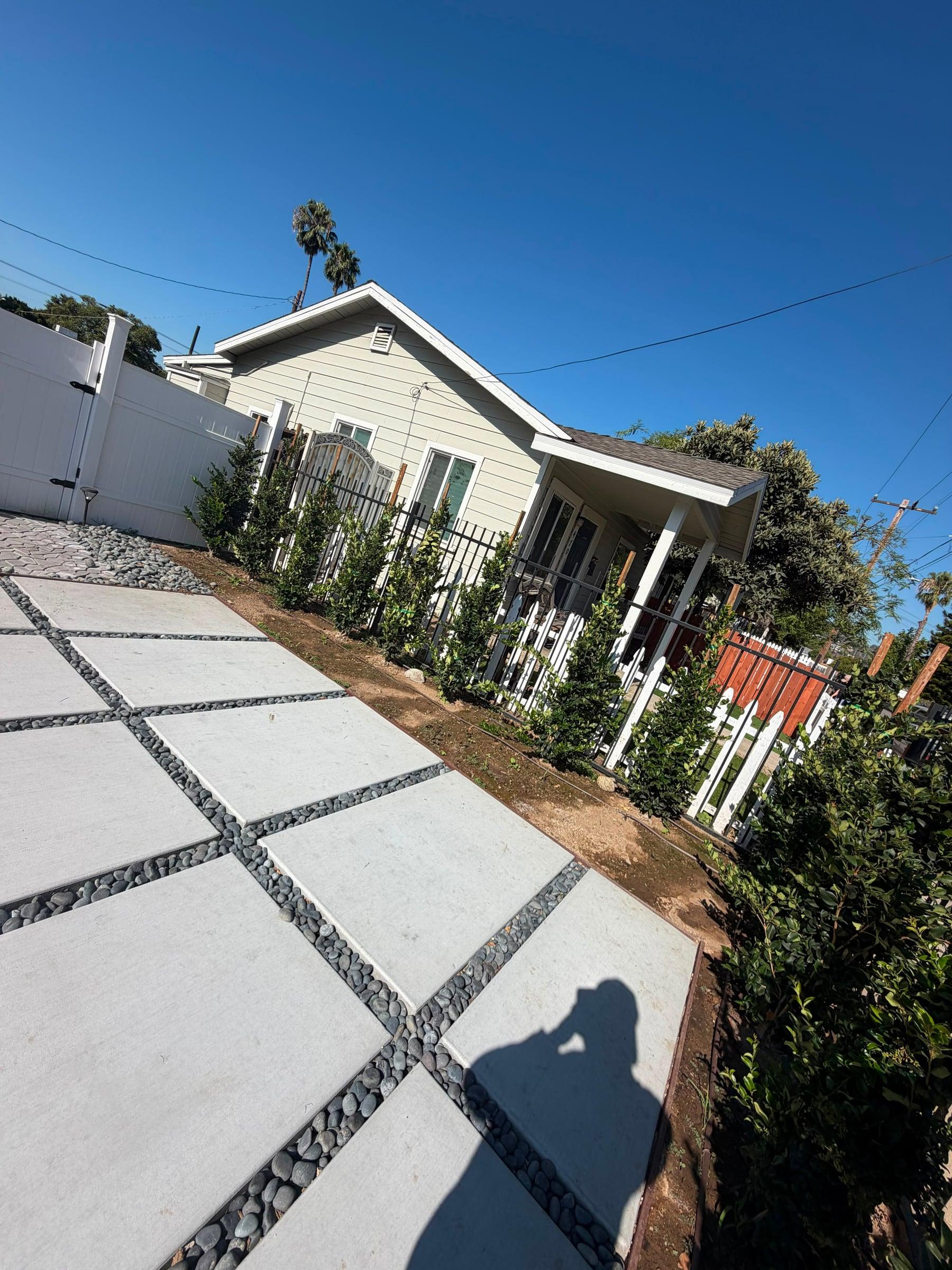 Paver walkway with river rock joints along a new hedge